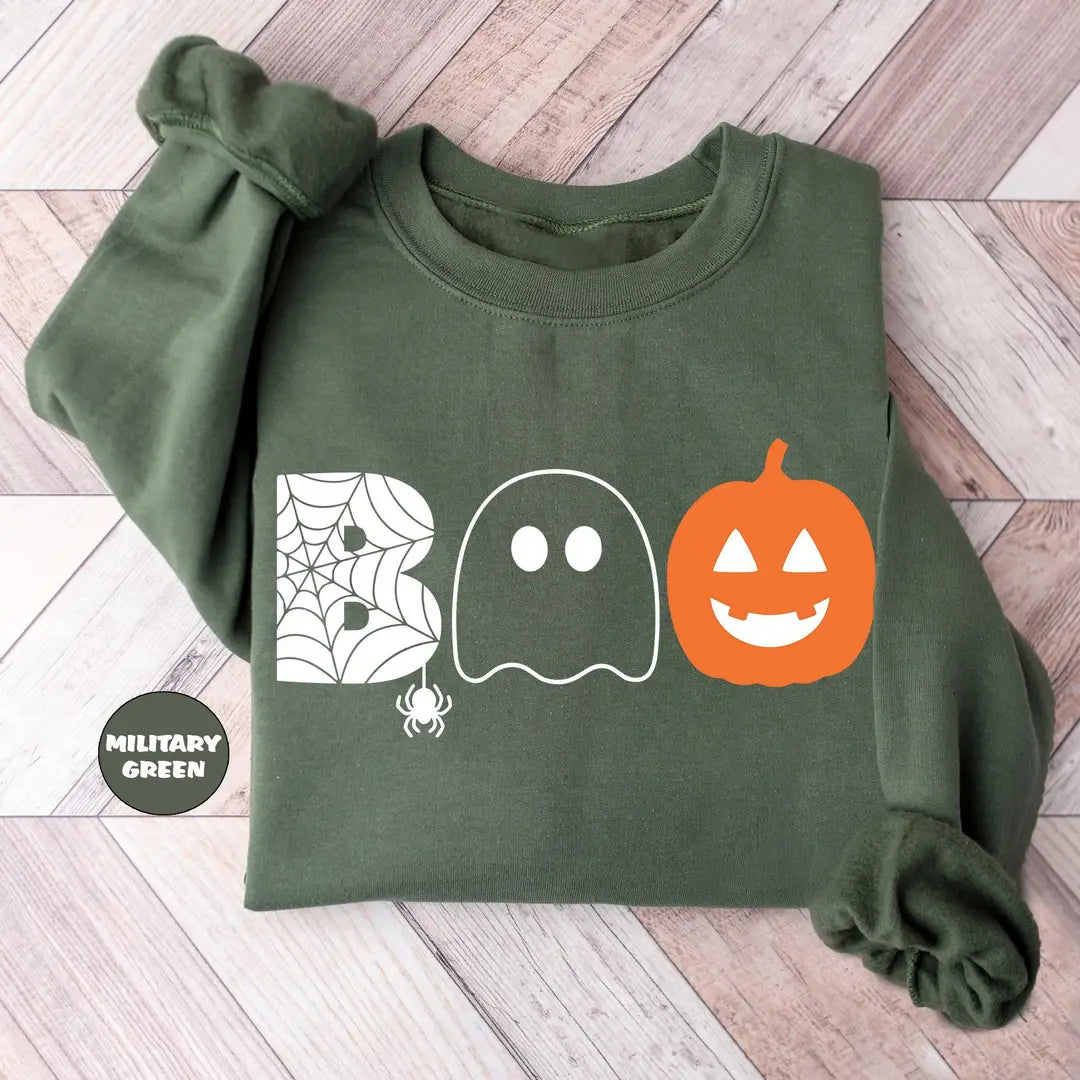 Military Green crewneck sweatshirt with the word boo spelled with a spider web letter, a ghost and a jack-o-lantern, flat lay view.