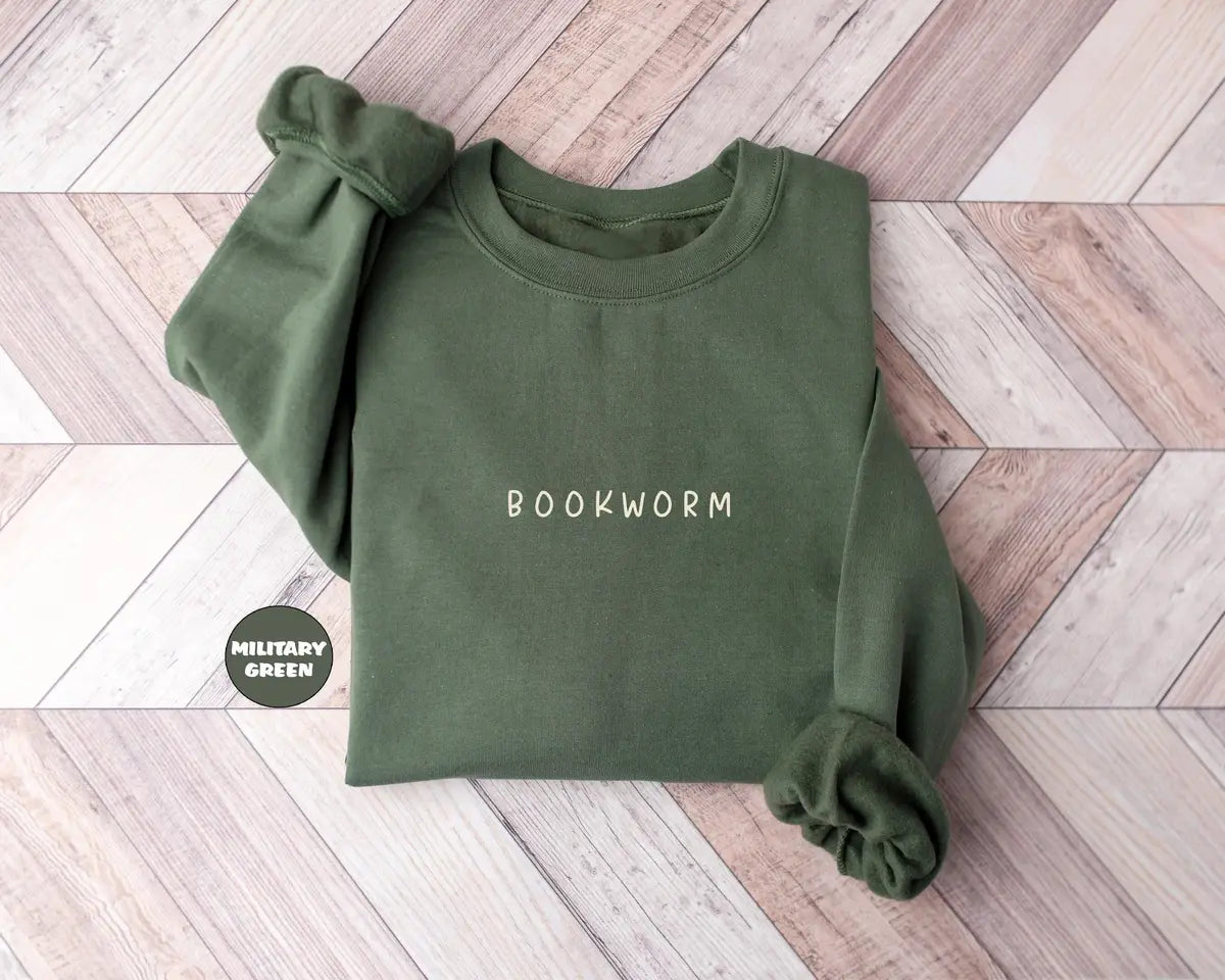 Military Green crewneck sweatshirt with small minimal lettering that reads bookworm on the chest, flat lay view.