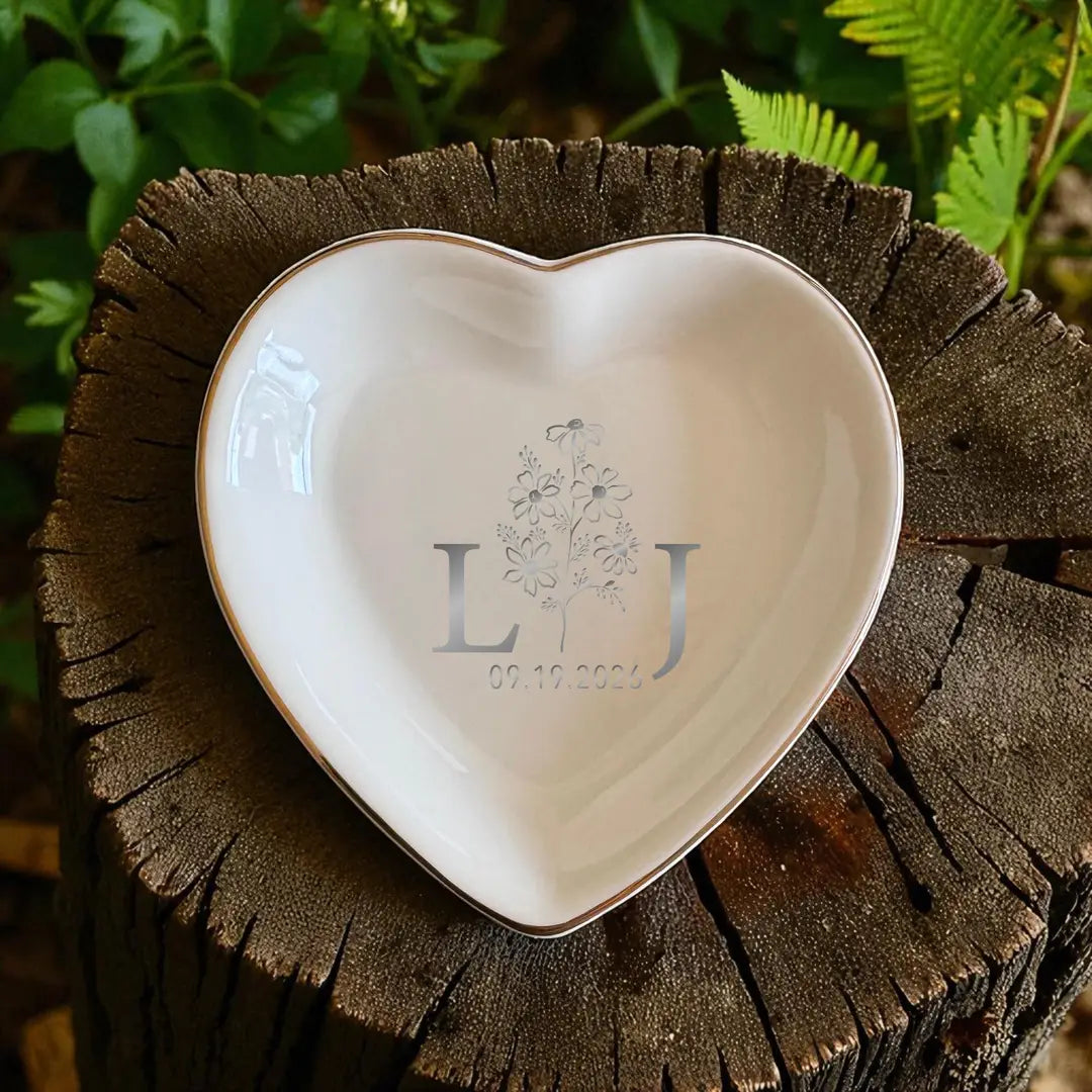 Ceramic ring dish with gold rim and silver initials with a date, on a tree stump