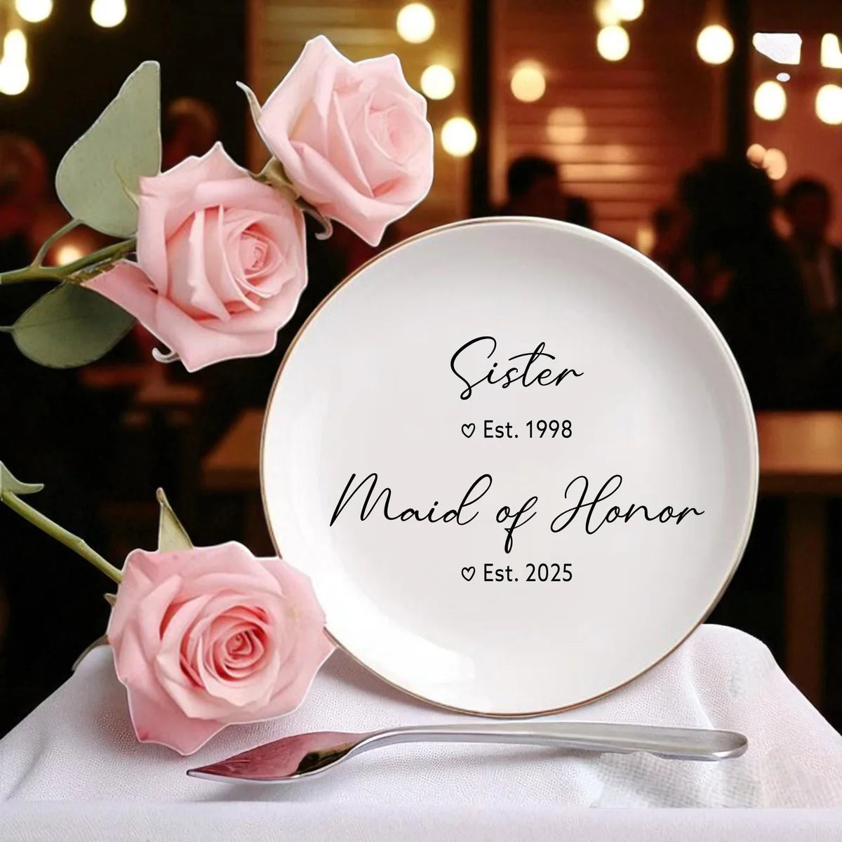 Round ceramic maid of honor ring dish with Sister Est. 1998 and Maid of Honor Est. 2025 text, styled with pink roses and warm lights