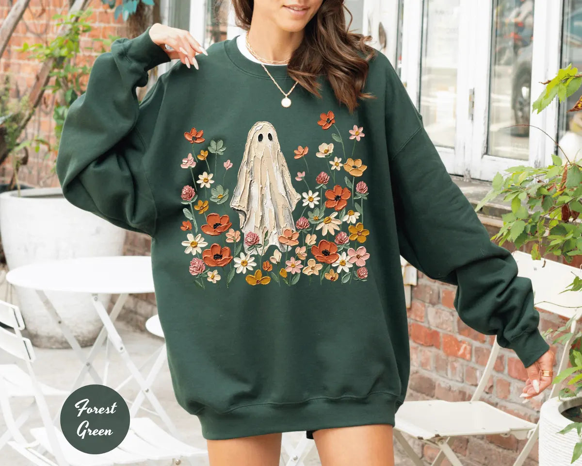 Forest Green crewneck sweatshirt with printed a ghost standing in a field of autumn wildflowers, worn by a model.