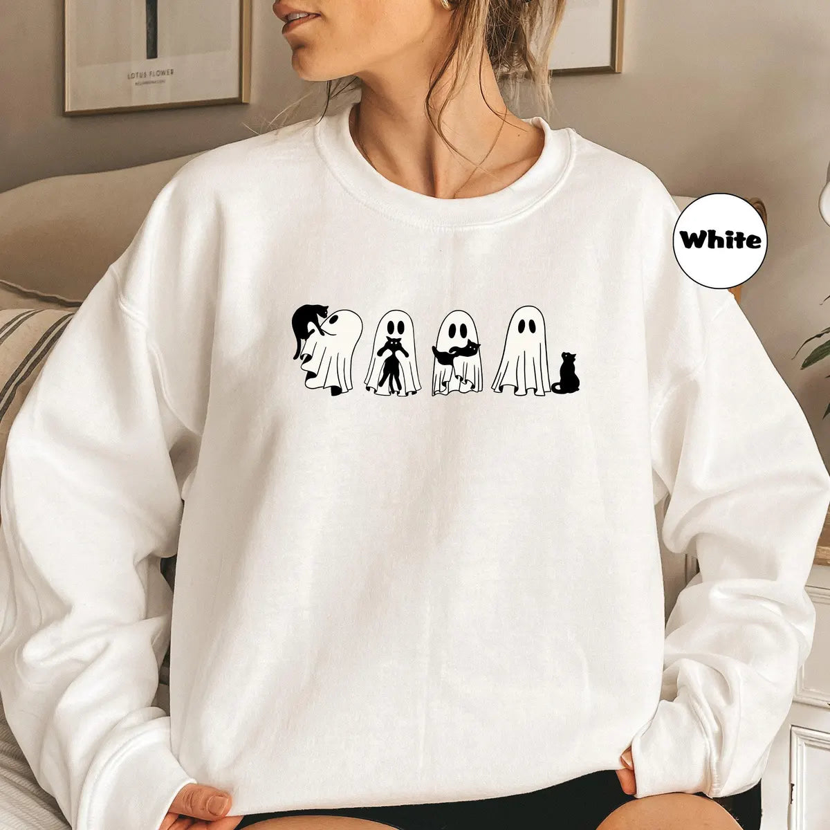 White crewneck sweatshirt with four ghosts and a black cat in a row, worn by a model.