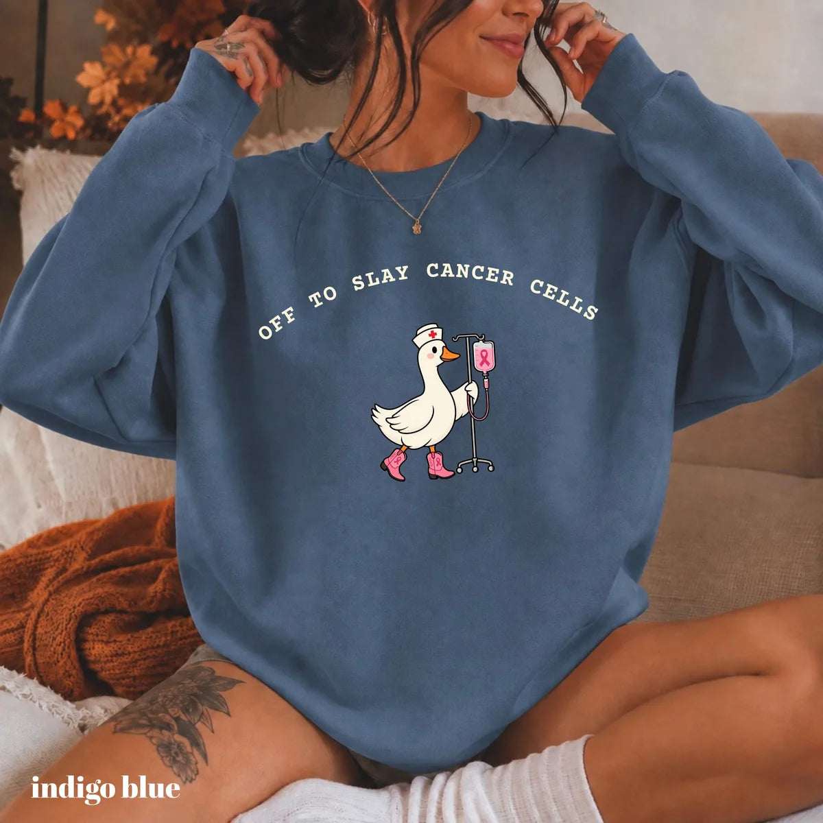 Indigo Blue crewneck sweatshirt with printed a nurse goose in pink boots with an IV pole and the words off to slay cancer cells, worn by a model.