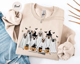 Sand crewneck sweatshirt with printed ghost dogs with witch hats, pumpkins and bats, flat lay view.