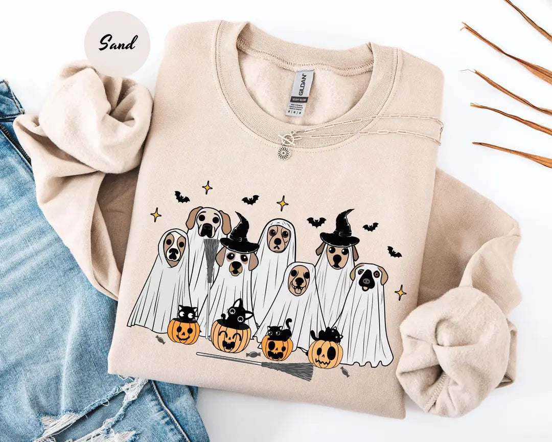Sand crewneck sweatshirt with printed ghost dogs with witch hats, pumpkins and bats, flat lay view.