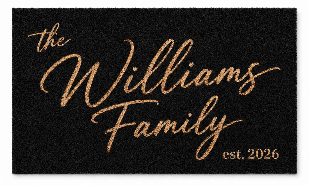 Flat view of a black faux coir doormat with a gold-tone script family name and established year