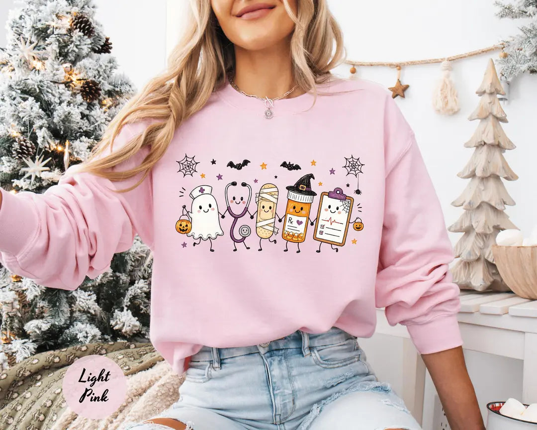 Light Pink crewneck sweatshirt with a ghost, stethoscope, bandage and medical chart characters with Halloween details, worn by a model.