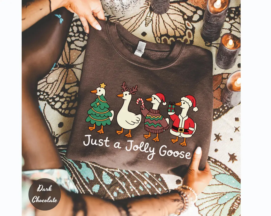 Dark Chocolate crewneck sweatshirt with geese dressed as a Christmas tree, reindeer and Santa above the words just a jolly goose, flat lay view.