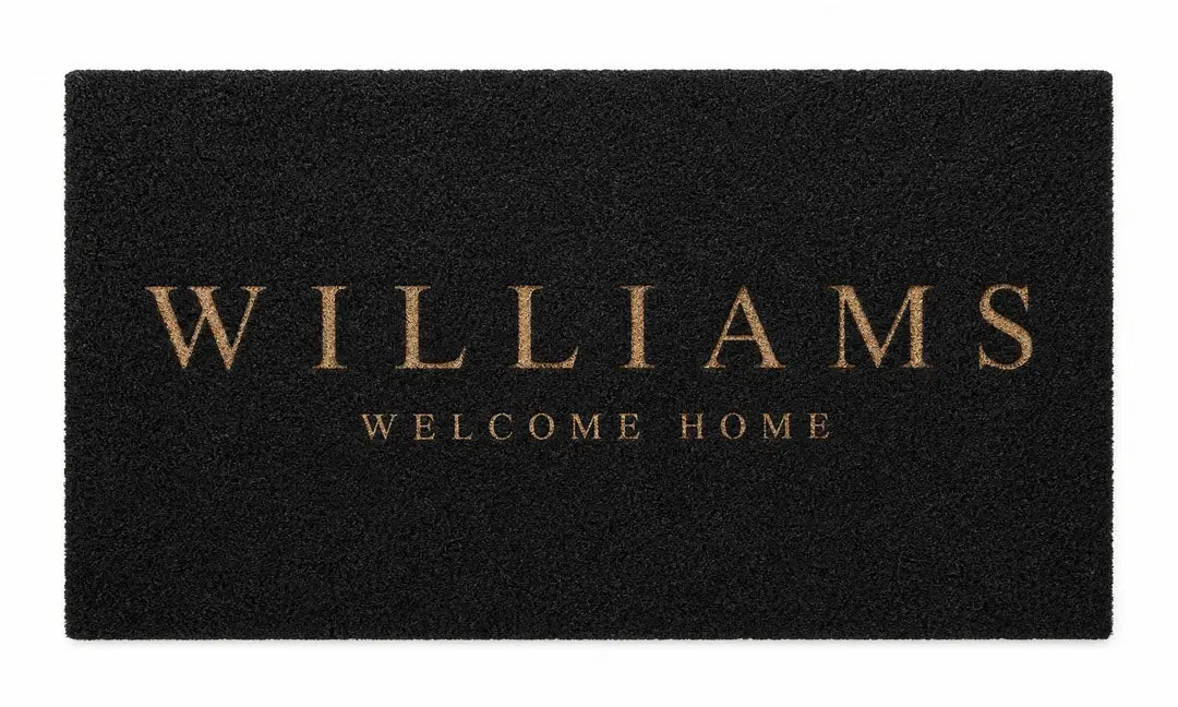Flat view of a black doormat with a gold Williams Welcome Home design