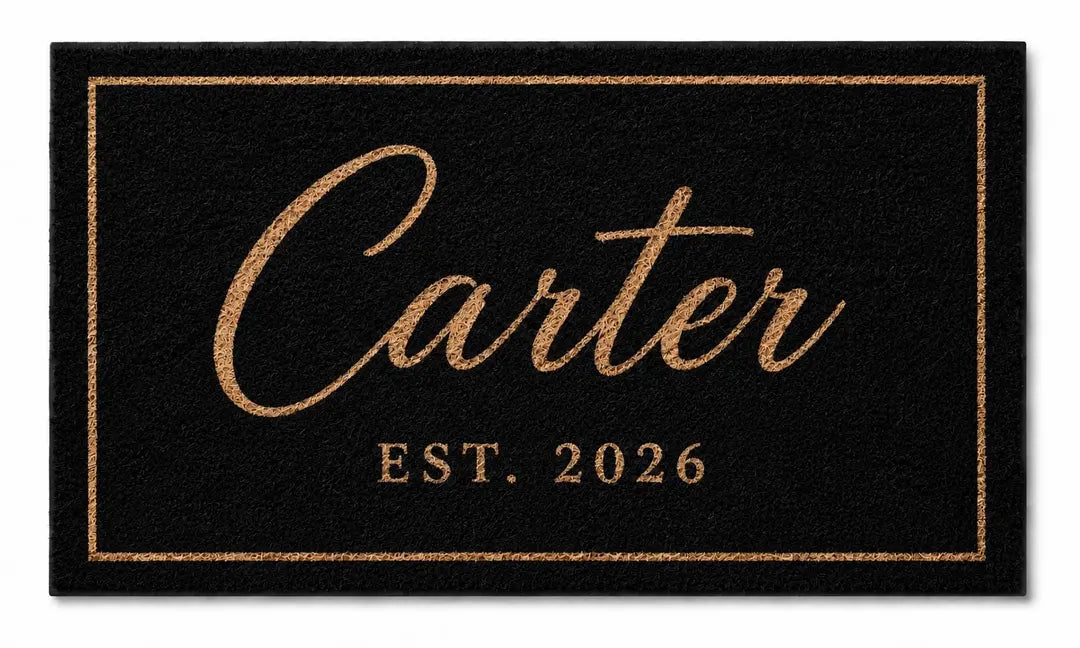 Flat view of a black faux coir doormat with a gold-tone script surname, established year, and thin border