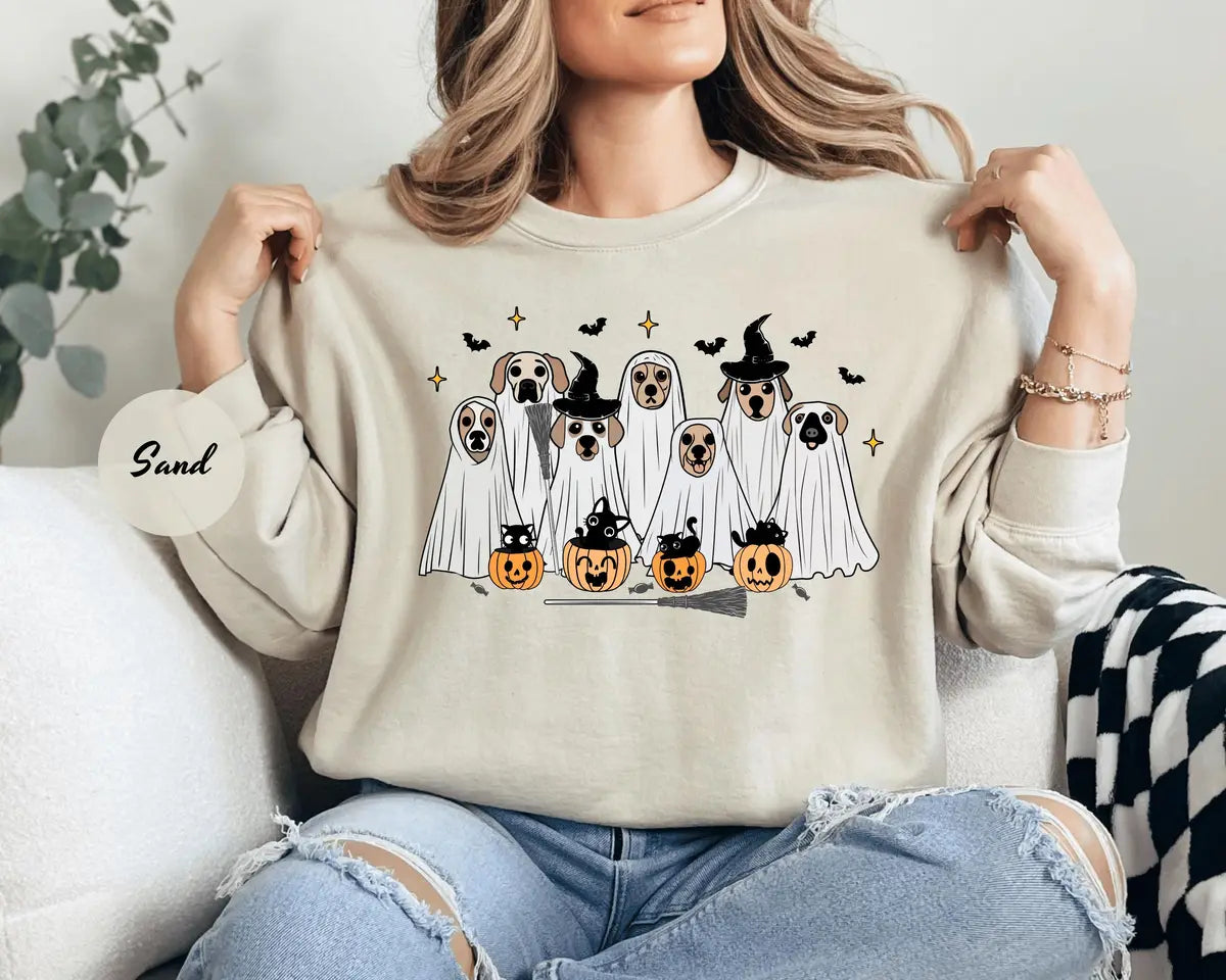 Sand crewneck sweatshirt with printed ghost dogs with witch hats, pumpkins and bats, worn by a model.