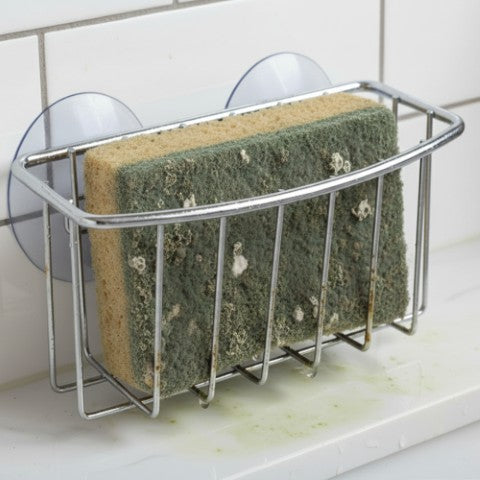 Metal sponge holder with sponges on a tiled wall