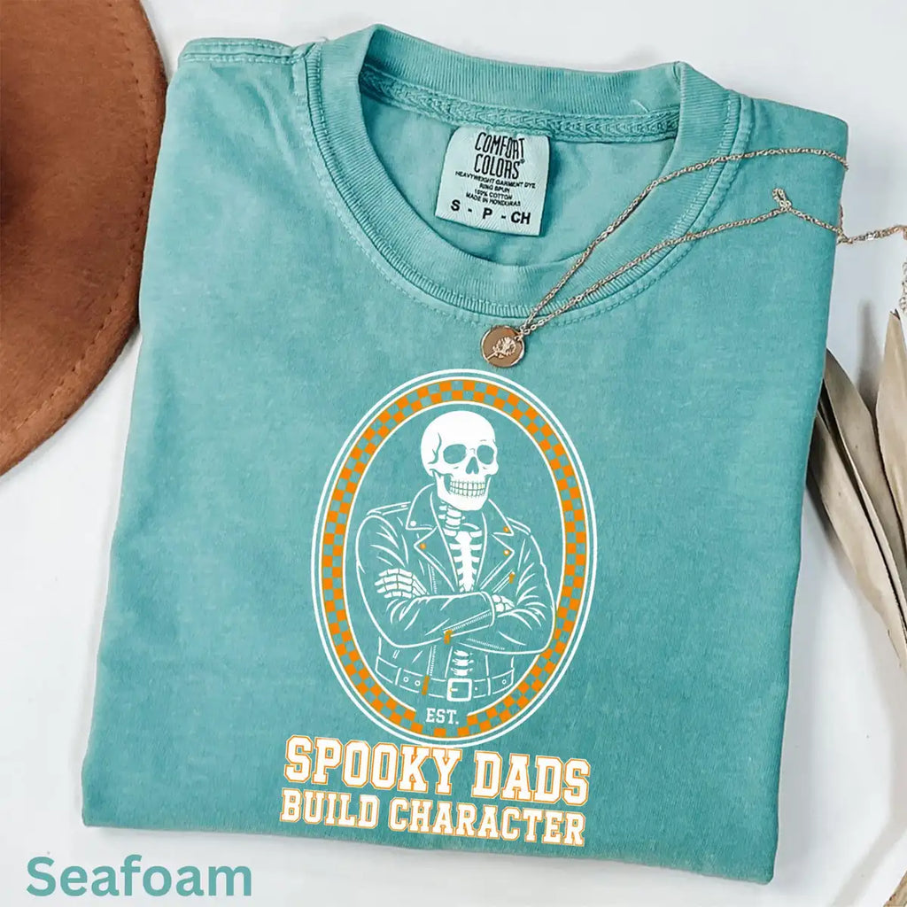 Comfort Colors T-shirt flatlay in Seafoam color featuring Spooky Dads Build Character skeleton graphic