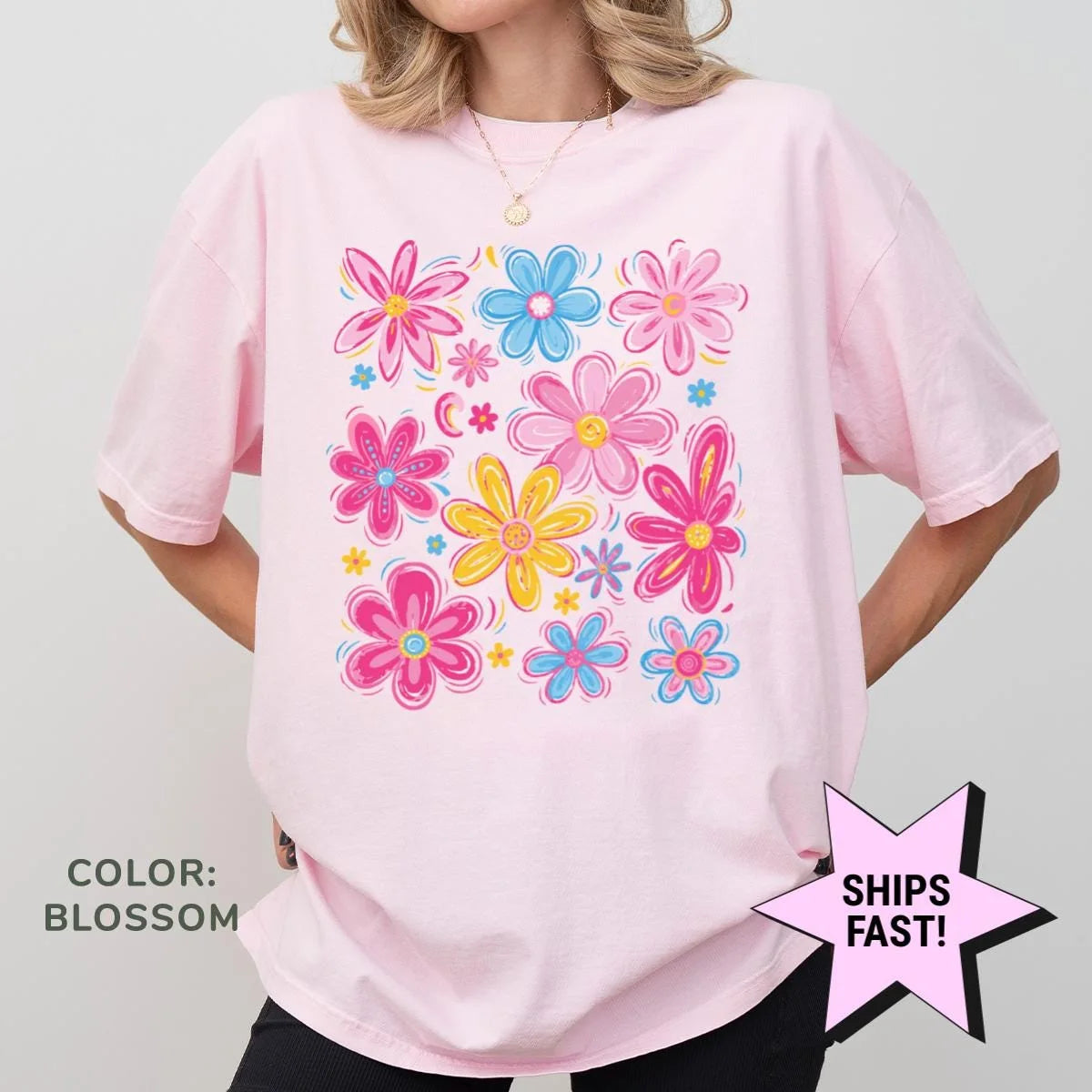Woman in a Blossom pink Comfort Colors tee, hands on hips, with a wildflower print in hot pink, sky blue and yellow