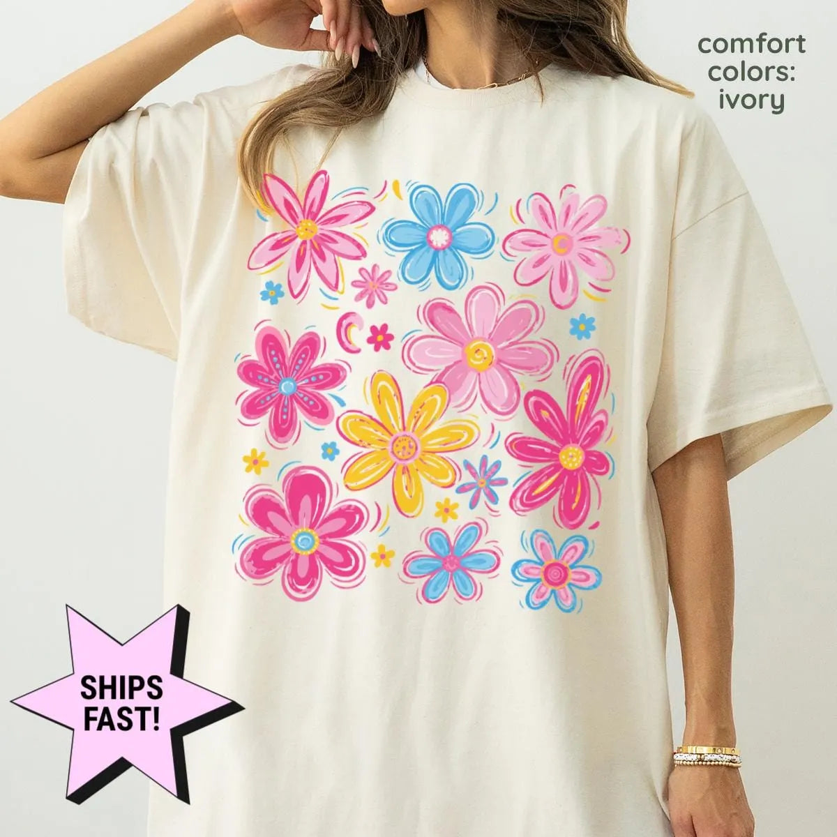 Woman in an Ivory Comfort Colors tee, hand at her hair, with a large pink, blue and yellow wildflower print