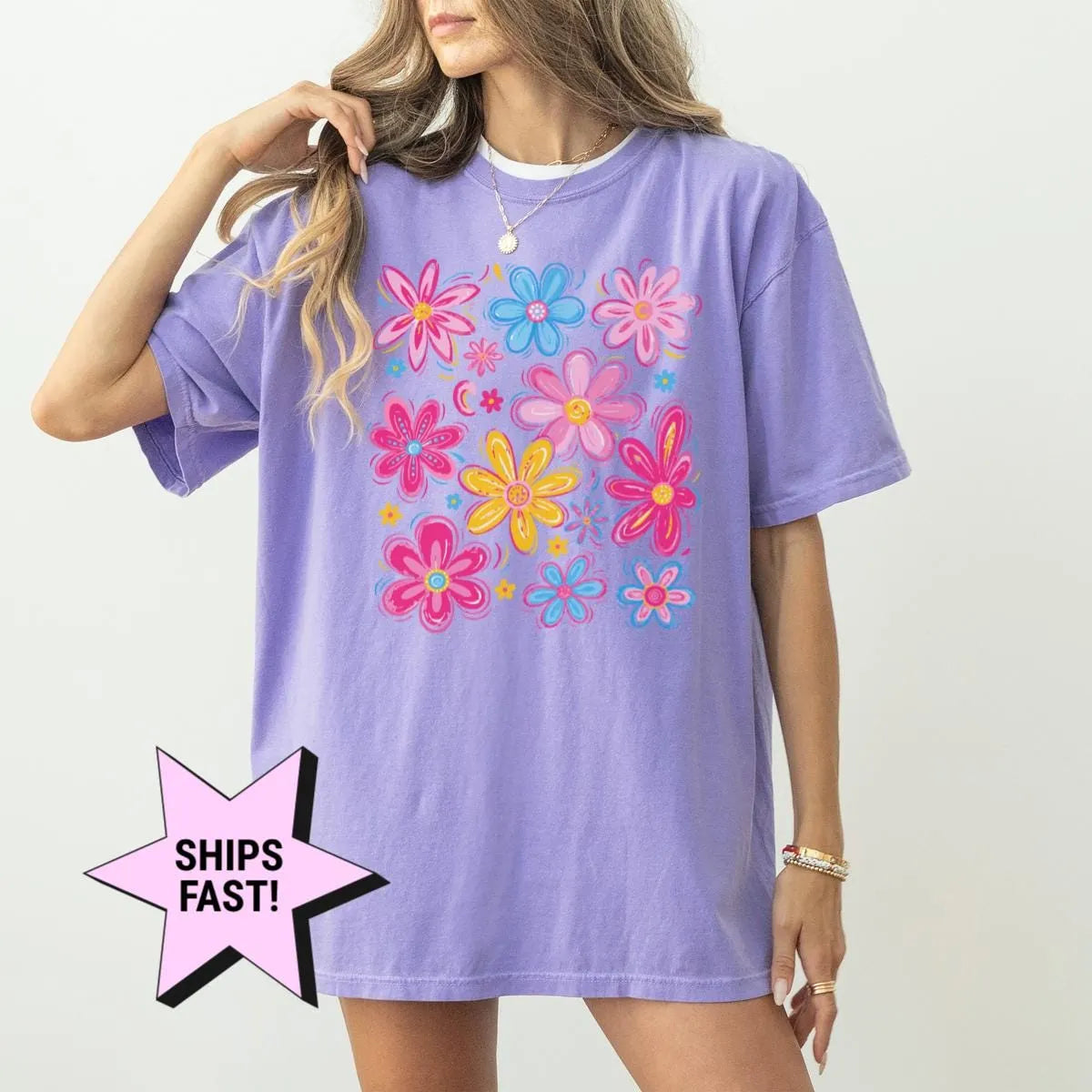 Woman in a Violet Comfort Colors tee with a bright hand-drawn wildflower cluster in pink, blue and yellow