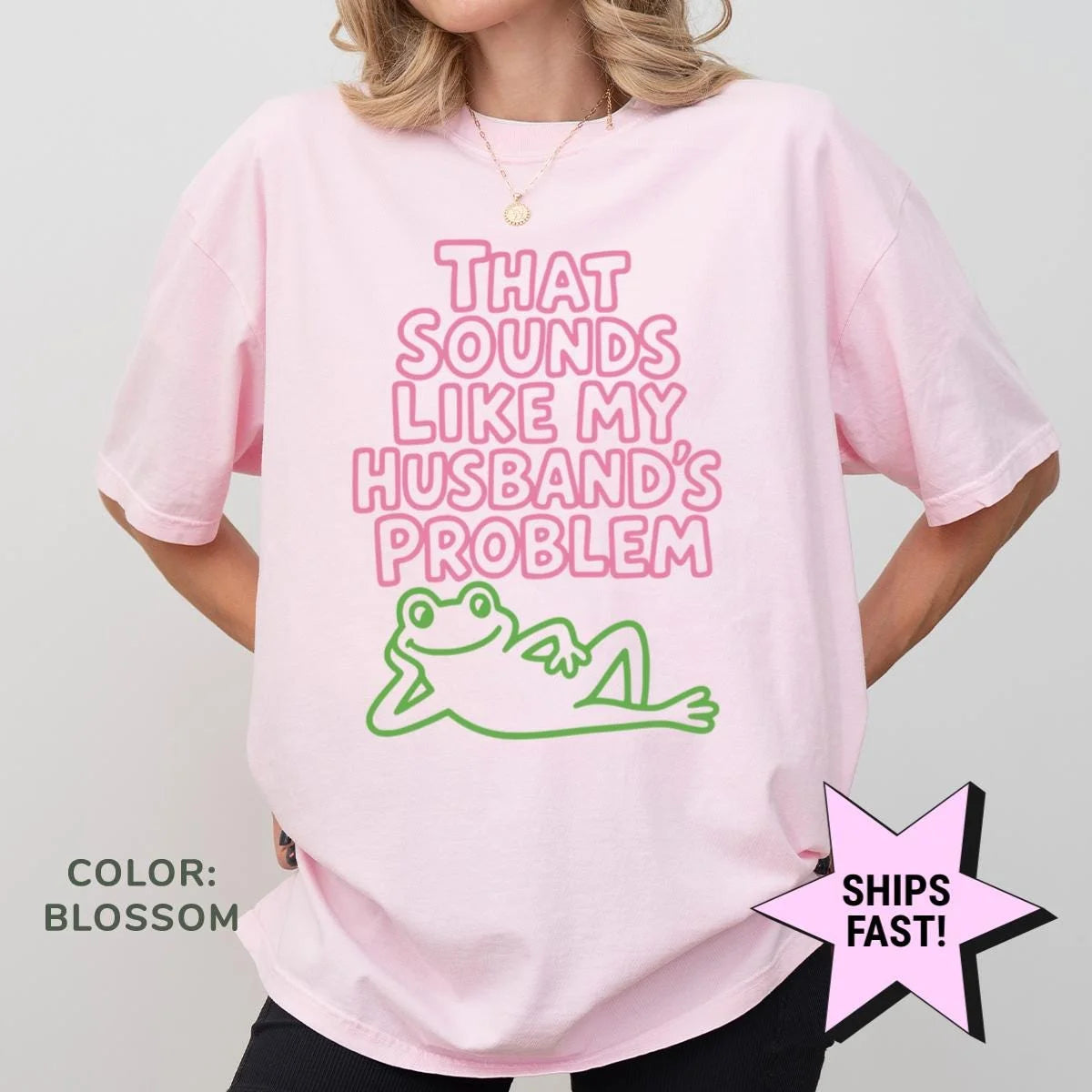 Woman in a Blossom pink Comfort Colors tee, hands on hips, with outlined husband's problem text above a green frog