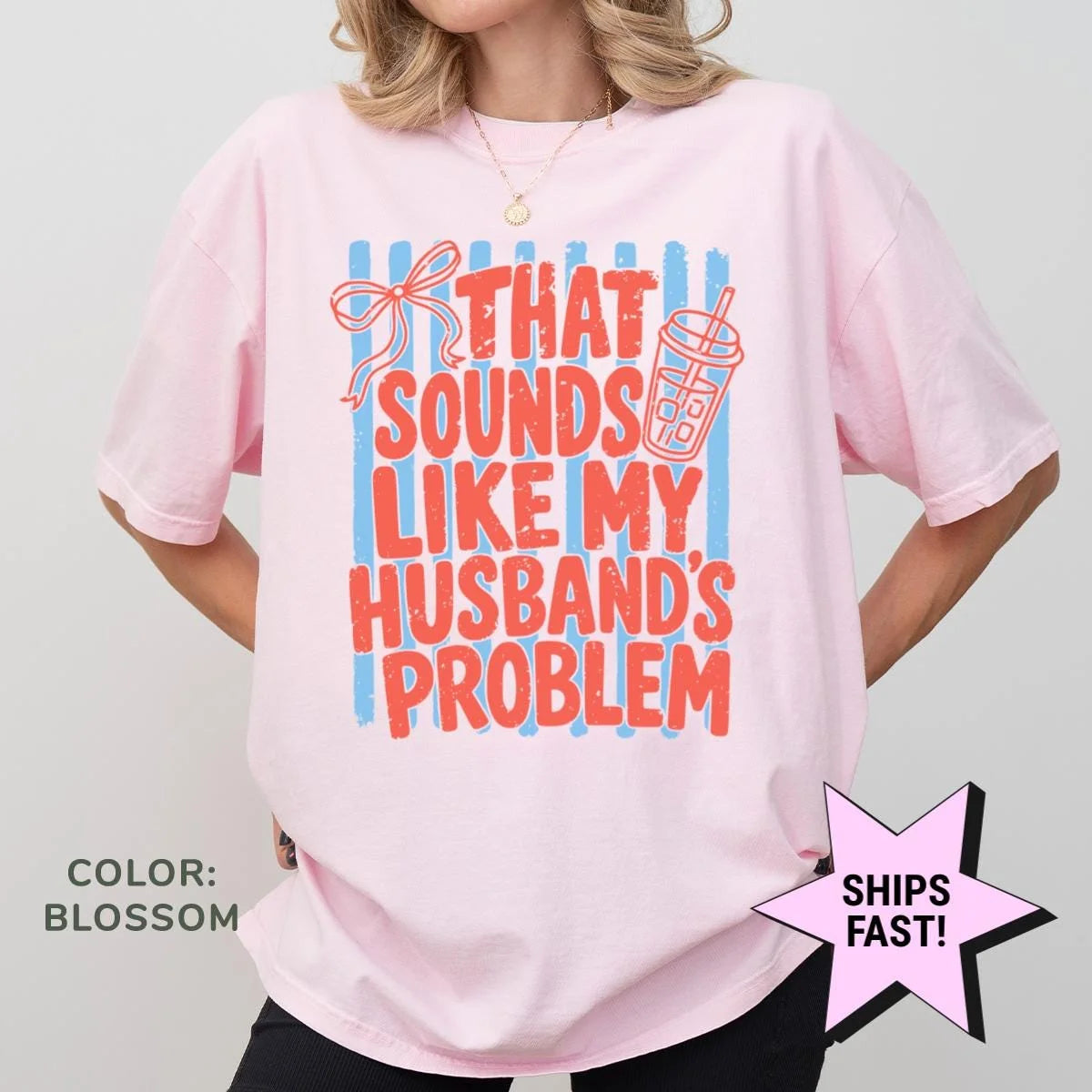 Woman in a Blossom pink Comfort Colors tee, hands on hips, with red husband's problem block letters over blue stripes