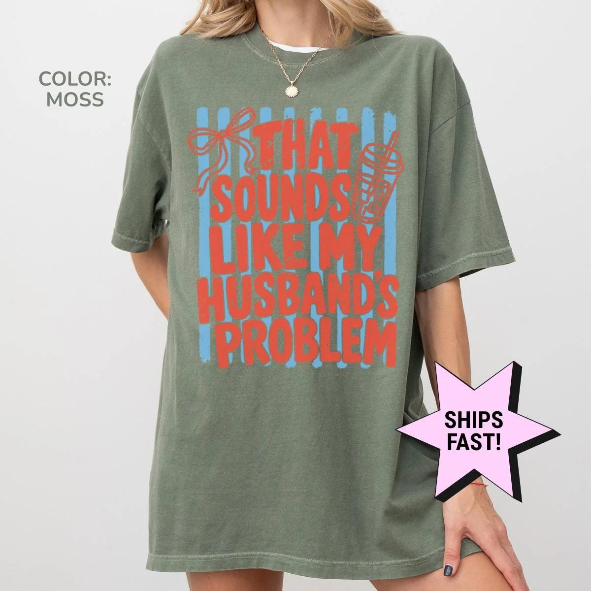 Woman in a Moss green Comfort Colors tee, hand at her side, with red husband's problem lettering, a bow and an iced drink