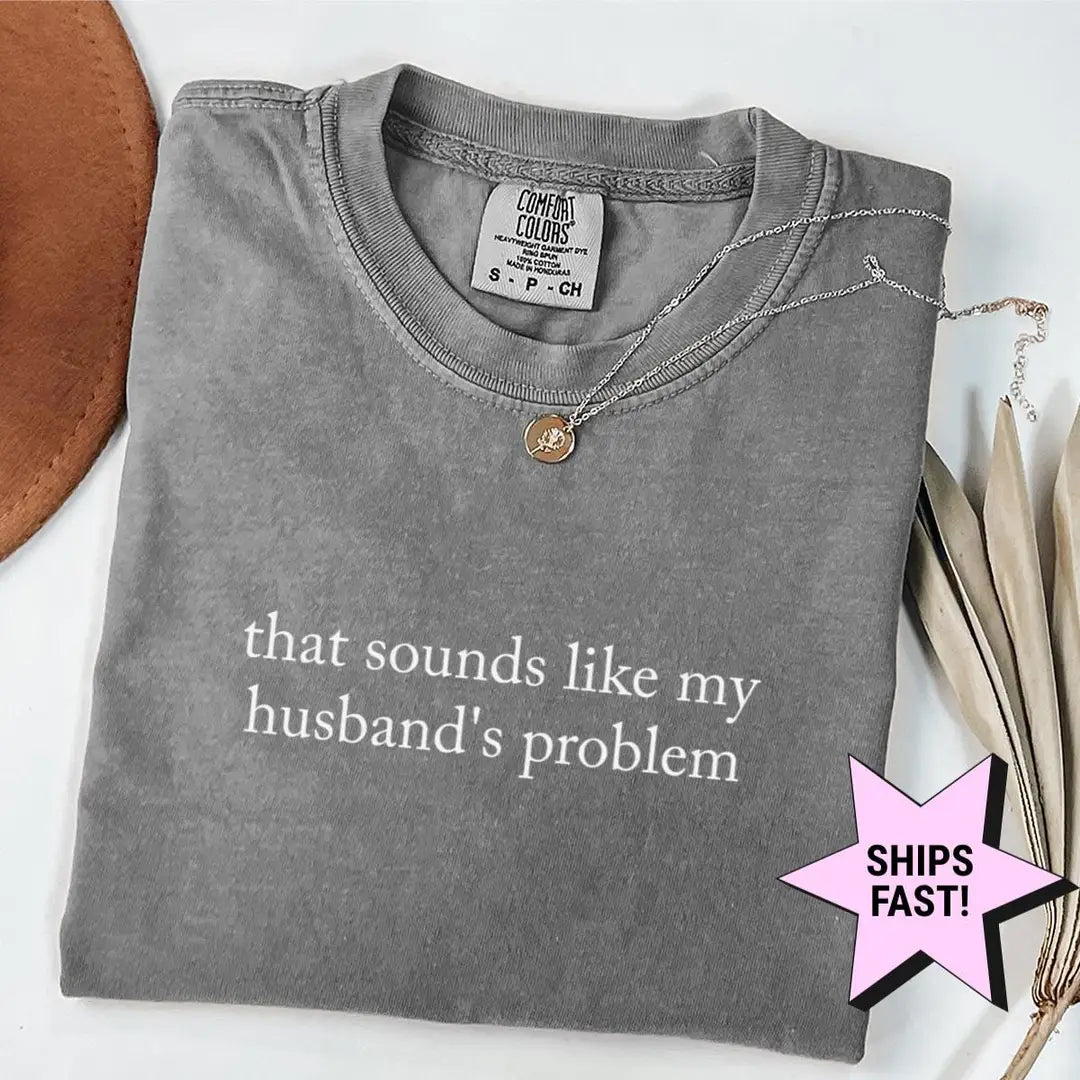 Folded Pepper Comfort Colors tee with that sounds like my husband's problem in white serif, necklace and brown hat