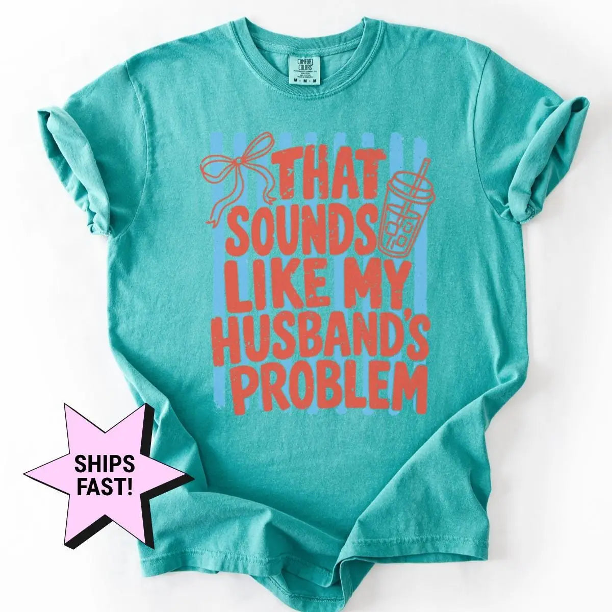 Seafoam teal Comfort Colors tee with sleeves rolled, flat on white, red husband's problem lettering, a bow and an iced drink