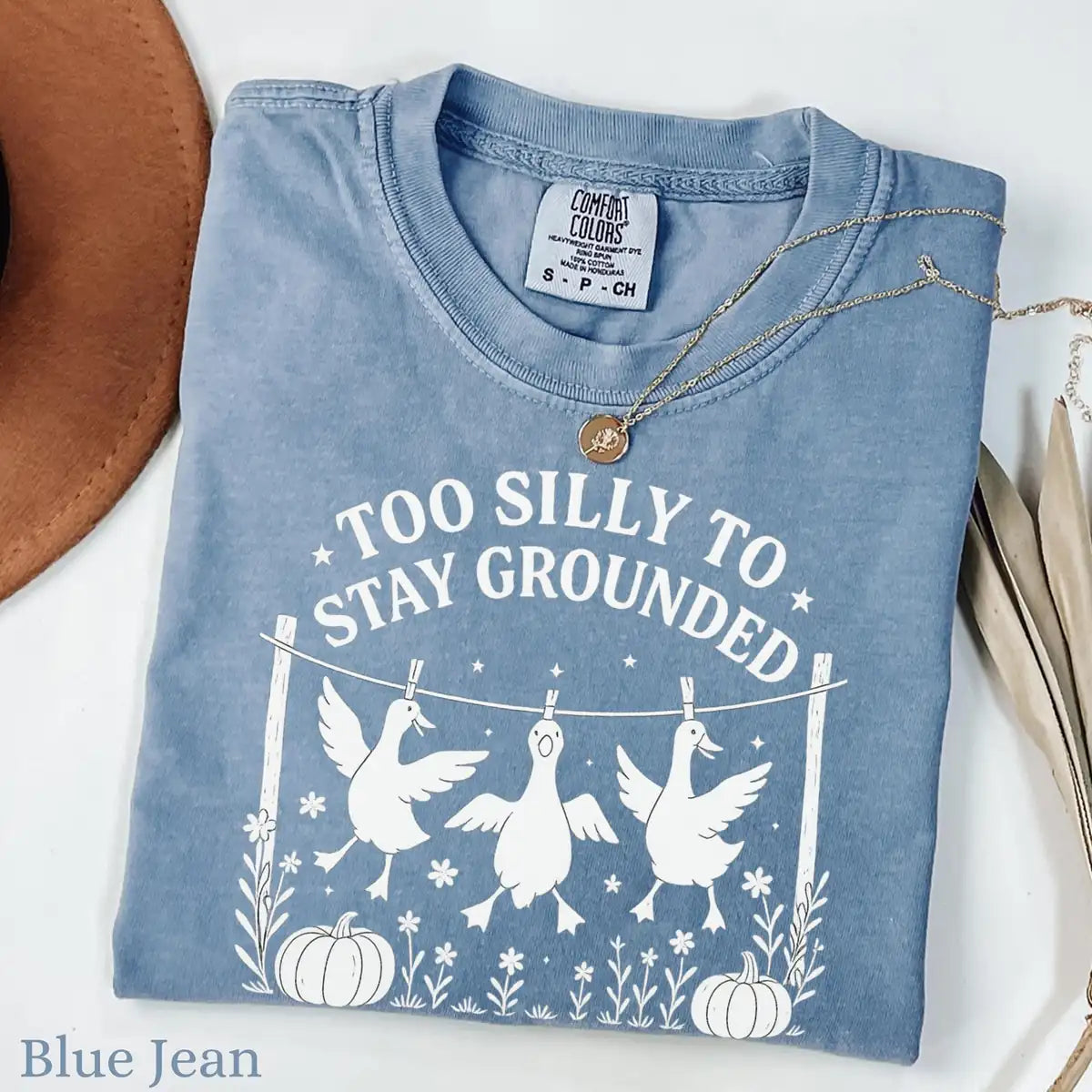 Comfort Colors T-shirt in Blue Jean color featuring Too Silly To Stay Grounded geese on clothesline graphic