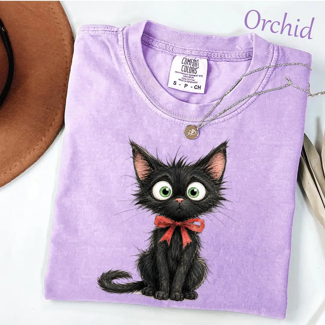 Folded Orchid lavender Comfort Colors tee with a wide-eyed black kitten in a red bow, necklace on the collar