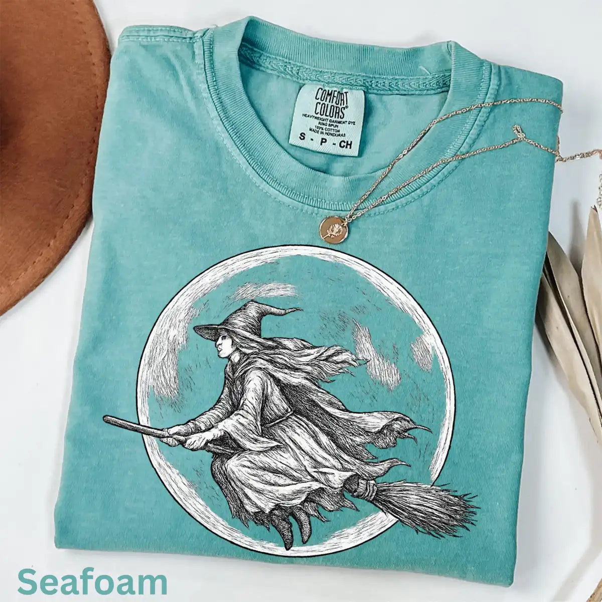 Comfort Colors T-shirt in Seafoam color featuring witch flying on broomstick in full moon graphic
