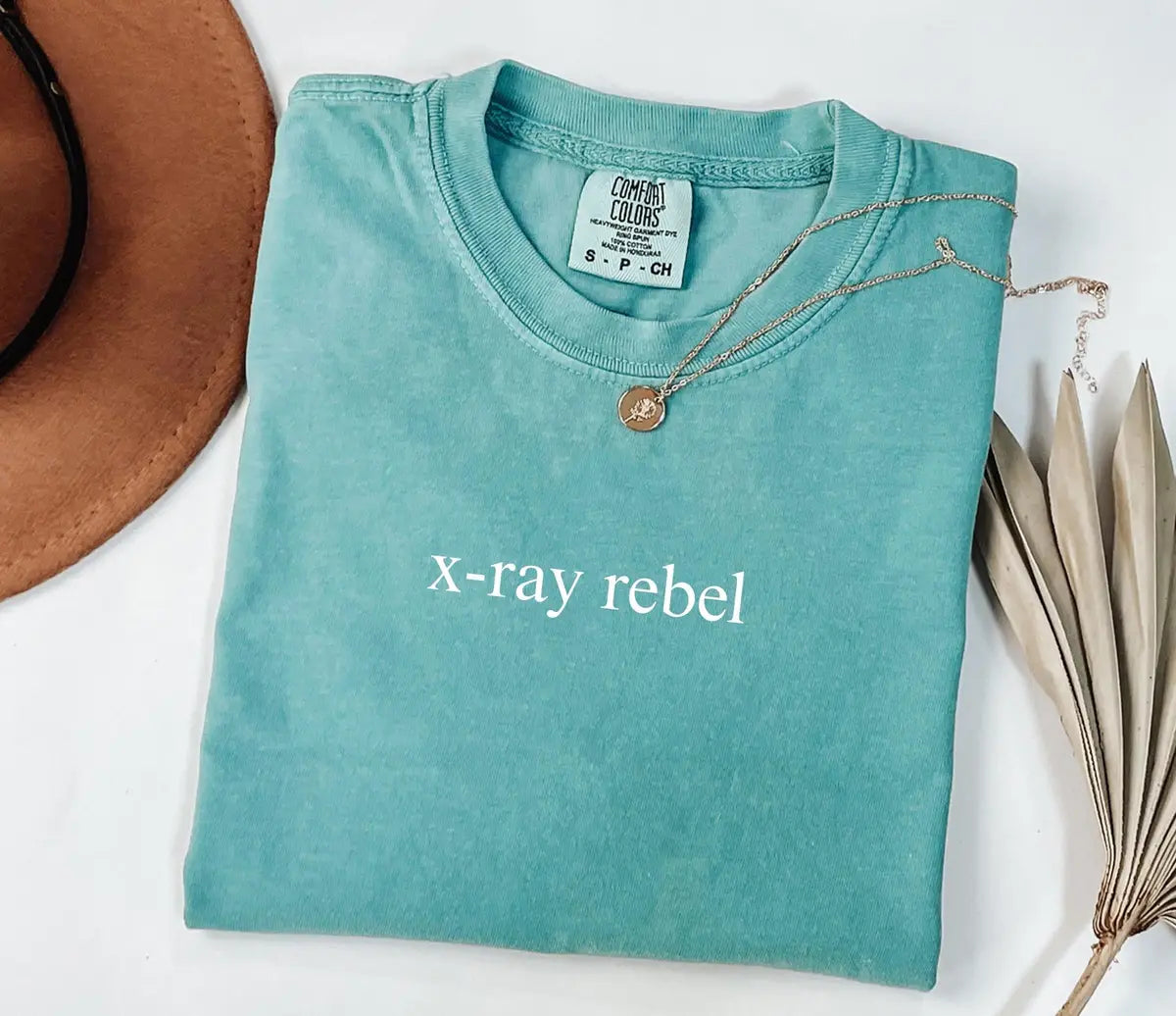 Seafoam Comfort Colors T-shirt with minimal X-Ray Rebel lettering.